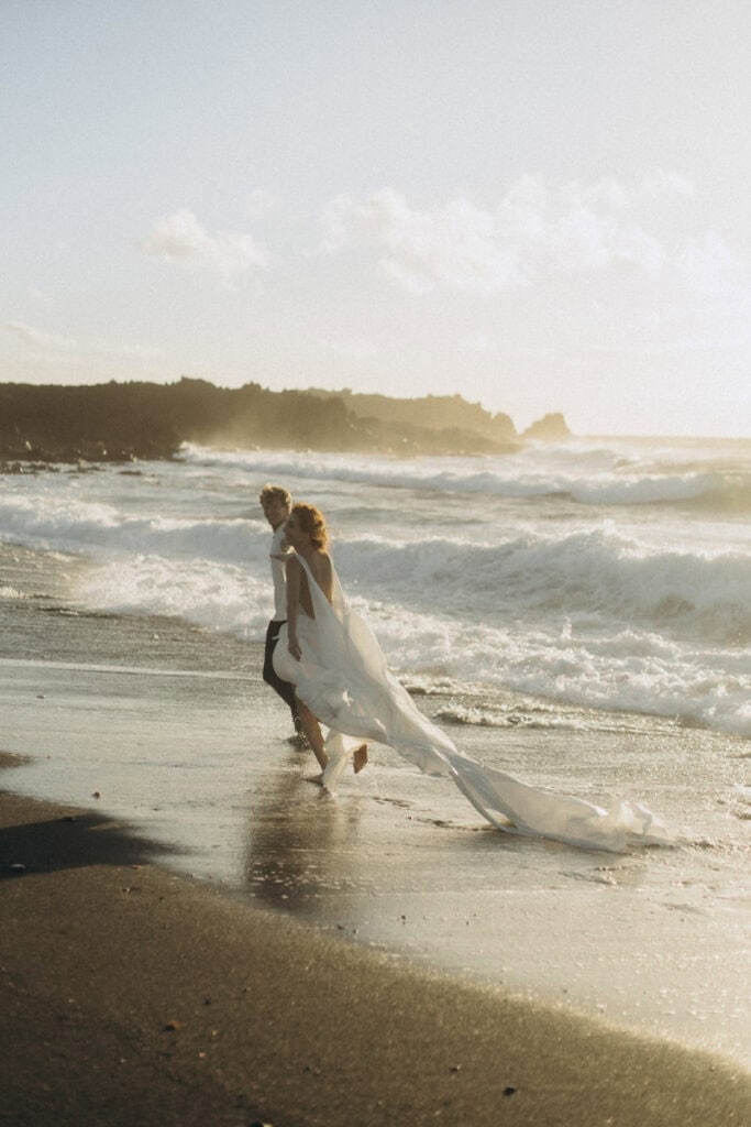 Braut im Hochzeitskleid am Strand bei Sonnenuntergang, romantische Hochzeitsatmosphäre.