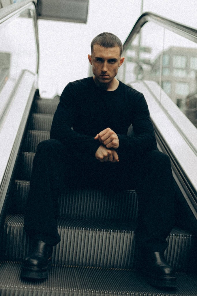 Junge Mann auf Rolltreppe in Düsseldorf, professionelles Fotoshooting, urbanes Ambiente.