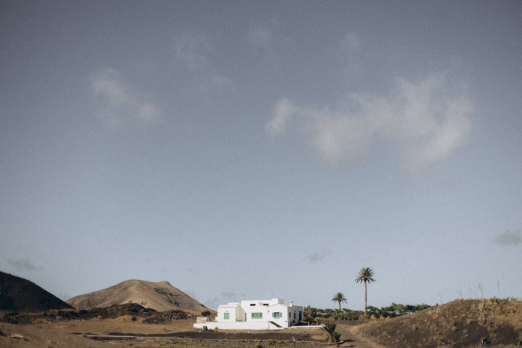 Veronika Haas am Strand mit Blick auf weiße Häuser und Palmen auf Lanzarote.