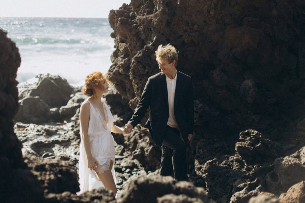 Veronika Haas beim intimen Engagement am Strand von Lanzarote, umgeben von Felsen und Meer.